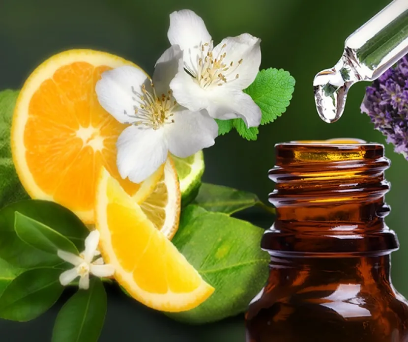 Close-up of an amber glass essential oil bottle with a dropper releasing a liquid drop above it.