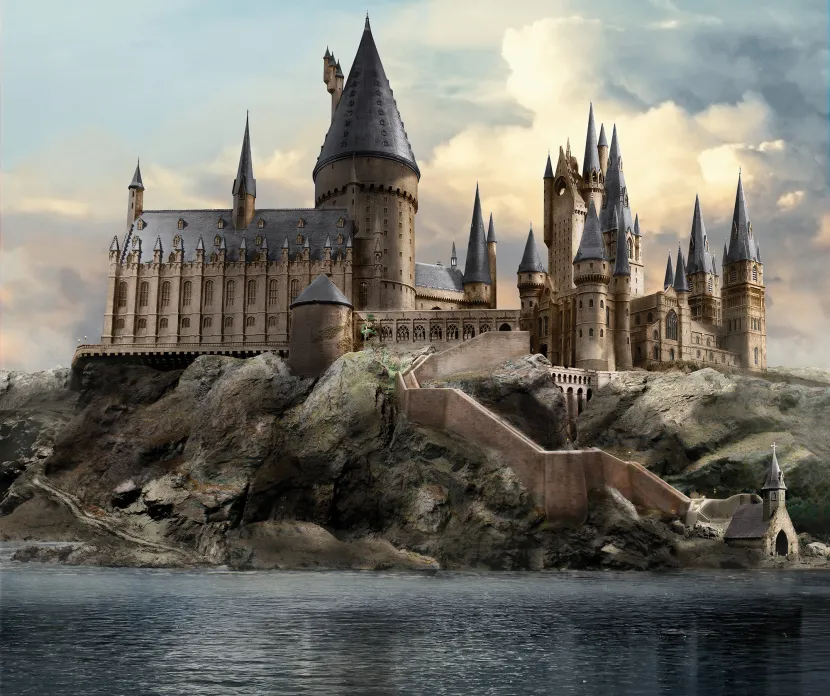 Large magical stone castle with tall pointed towers and spires, built on a rugged cliff overlooking a calm lake at sunset, resembling a fantasy school of wizardry.