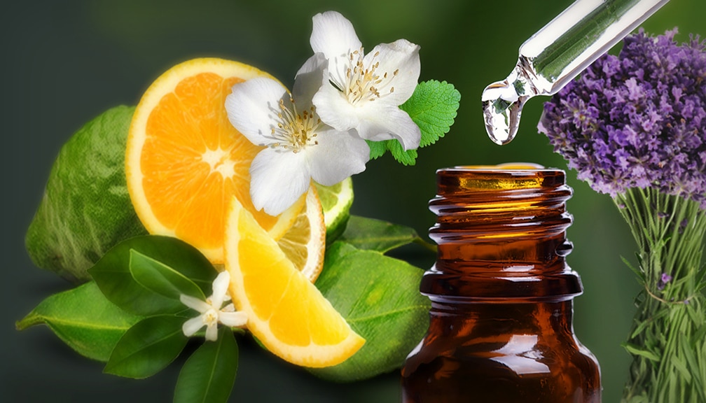 Close-up of an amber glass essential oil bottle with a dropper releasing a liquid drop above it.
